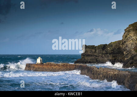 UK weather - Rough seas breaking over the pier at Portreath Harbour in Cornwall. Stock Photo