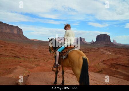 red haired boy on horse in monument valley in shorts Stock Photo