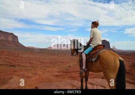 red haired boy on horse in monument valley in shorts Stock Photo