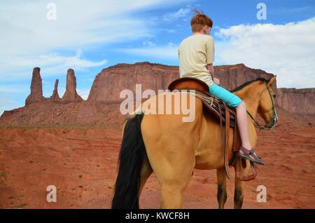 red haired boy on horse in monument valley in shorts Stock Photo