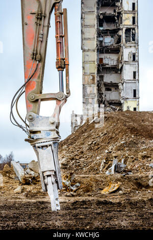 Closeup of hidraulic arm for building demolition demolished highrise industrial building on background Stock Photo