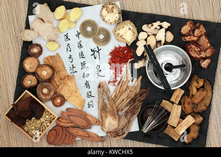 Chinese moxa sticks used in moxibustion therapy and acupunture needles with herbs, feng shui coins and calligraphy script on rice paper. Stock Photo