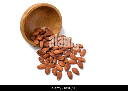 Almonds falling from brown bowl on a white background Stock Photo