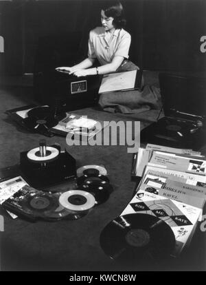 Record players matching the three types of records available in 1949. Young woman seated on floor with record players and 78 r.p.m.(revolutions per minute), 45 r.p.m. and 33 1/3 r.p.m. records. - (BSLOC 2014 17 117) Stock Photo