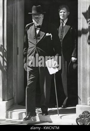 Prime Minister Winston Churchill leaving 10 Downing Street to speak to Parliament on June 18, 1940. He announced Britain has more than 1,250,000 men under arms and Britain would fight alone 'for years' if necessary. Behind him is Brendan Bracken, a Conservative Party Parliamentary Private Secretary to the Prime Minister. The Germans had just defeated France and British troops had retreated from Dunkirk to England. - (BSLOC 2014 17 34) Stock Photo