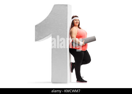 Full length portrait of an overweight woman with an exercise mat leaning against a cardboard number one isolated on white background Stock Photo