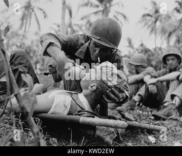 US Navy corpsman gives a drink to wounded Marine on Guam, July 1944, during World War 2.  (BSLOC 2017 20 187) Stock Photo