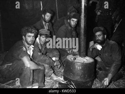 Released American and Australian POWs warming up by a stove. They are in the 24th Division medical clearing station after being returned to U.S. lines by Chinese Communists, February 10, 1951. Korean War, 1950-53. (BSLOC 2014 11 169) Stock Photo
