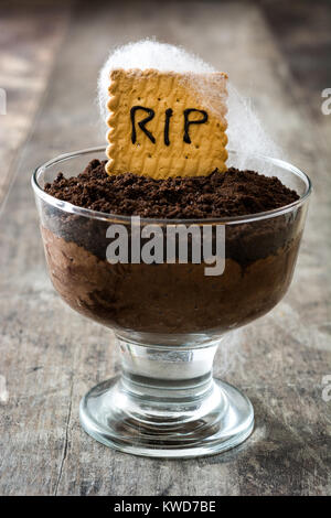 Funny Halloween chocolate mousse with tomb cookie on wooden table Stock Photo