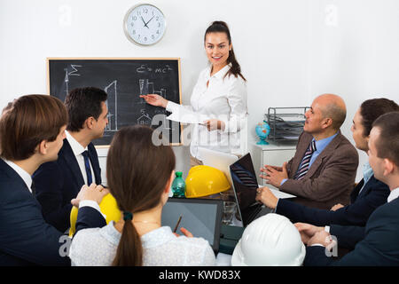 Team of successful energetic  engineers and architects discussing business project and smiling indoors Stock Photo