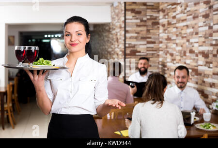 Happy female waiter showing country restaurant to visitors Stock Photo