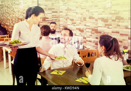 Positive waitress taking table order and smiling at tavern Stock Photo