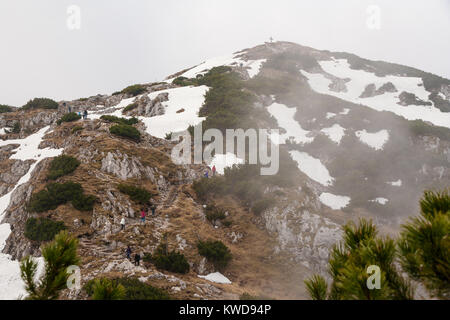 Ramblers reaching for the summit cross of Untersberg, Salzburg, Austria. Stock Photo
