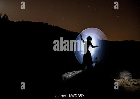Model posing at night and illuminated only with flashlights by means of the technique of the painting of light. Stock Photo