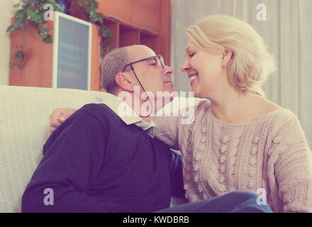 Portrait of happy elderly spouses sitting on sofa indoor Stock Photo