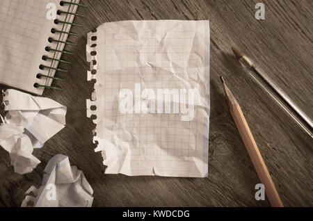 Empty crumpled pages and notebook lying on wooden surface Stock Photo