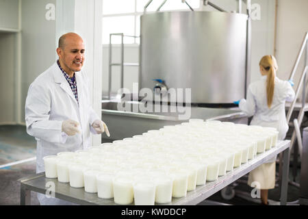 two  specialists in white coats working at cottage cheese production on dairy factory Stock Photo