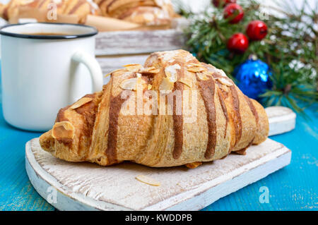 Croissants with almond flakes, coffee mug on a blue wooden background. Breakfast. Traditional French pastries. Stock Photo