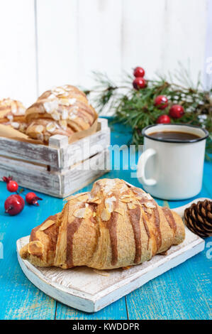 Croissants with almond flakes, coffee mug on a blue wooden background. Breakfast. Traditional French pastries. Stock Photo