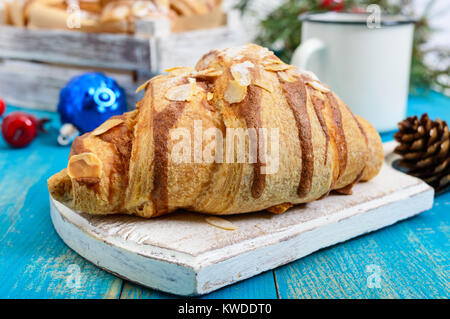 Croissants with almond flakes, coffee mug on a blue wooden background. Breakfast. Traditional French pastries. Stock Photo