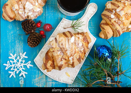 Croissants with almond flakes, coffee mug on a blue wooden background. Breakfast. Traditional French pastries. Stock Photo