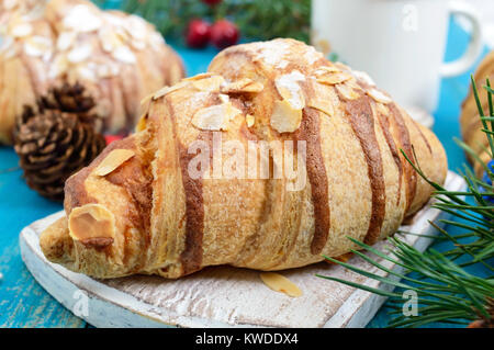 Croissants with almond flakes, coffee mug on a blue wooden background. Breakfast. Traditional French pastries. Stock Photo