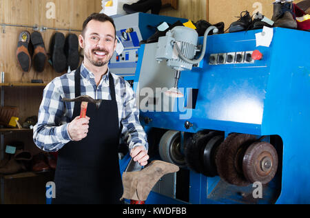 positive russian male worker fixing failed shoes in shoe repair workshop Stock Photo