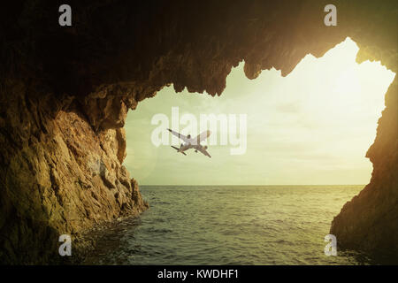 Airplane flying high in the sky above water surface Stock Photo
