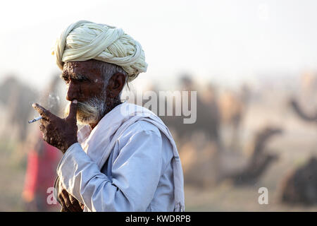Scene at Pushkar Camel Fair, portrait of senior trader wearing turban and smoking, Pushkar, Rajasthan, India Stock Photo