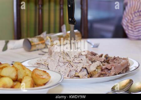 Sliced turkey with potatoes on the dinner table with Christmas cracker in the background Stock Photo