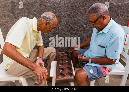 Two local men playing the traditional African board game called ouril, also known as oware, uril, ouri, ori and mancara, in Santa Maria, Africa Stock Photo