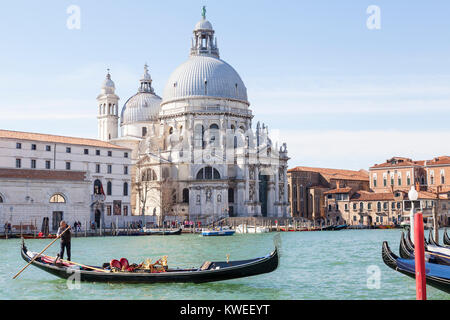 Gondolier  and gondola on the Grand Canal  in front of Basilica di Santa Maria della Salute, Venice, Italy in morning light Stock Photo