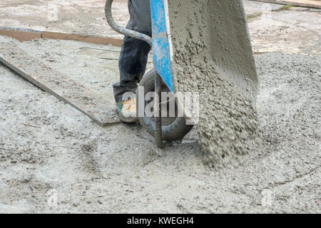 Workmen pouring concrete from a wheel barrow for vehicle hardstanding Stock Photo