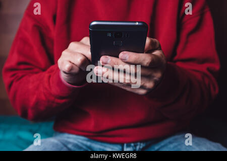 Caucasian male holding the smartphone with the left hand and touching in the touchscreen with one finger of the right hand. Stock Photo