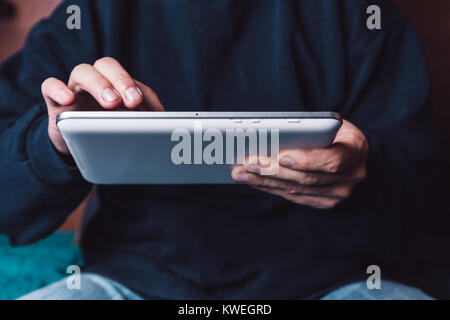 Caucasian male holding the tablet with the left hand and touching in the touchscreen with one finger of the right hand. Stock Photo