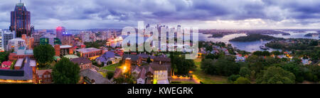 Panorama of SYdney city CBD from North Sydney office towers and high-rises at sunset across blurred blue sydney harbour waters towards major australia Stock Photo