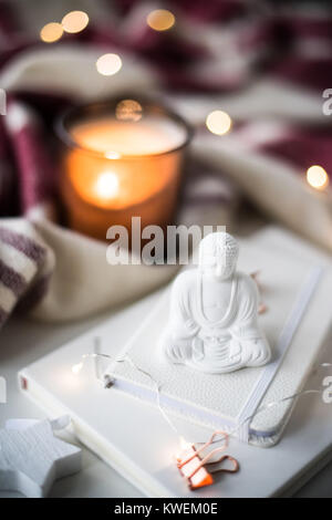 Little Buddha figurine with lights and candles, holiday new year still life Stock Photo