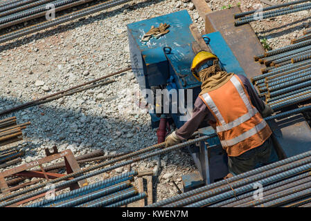 A worker on a construction site using a steel rod cutting machine Stock Photo