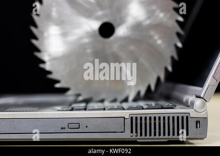 A laptop on a wooden table seen from the profile together with carpentry tools. Computer repair in a workshop. Black background. Stock Photo