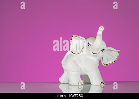 Closeup of white elephant made of porcelain, pink background Stock Photo