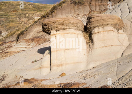 Hoodoos in the southern Alberta badlands, Canada. The hard ironstone cap rock protects the softer underlying sandstone from erosion. Stock Photo