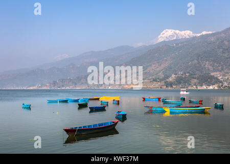 Traditional wooden rowbaots in Phewa lake in Pokhara, at the feet of the Annapurna mountain range in Nepal in South Asia. Stock Photo