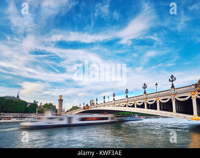 Ship passing under Alexandre III Bridge in Paris, long exposure to emphasize the movement. This image is toned. Stock Photo