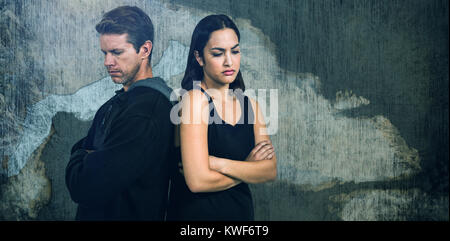 Composite image of sad couple with arms crossed standing back to back Stock Photo