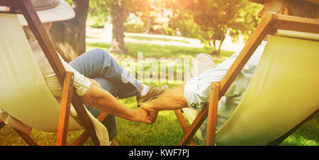 Mature couple sitting in deck chairs at park Stock Photo