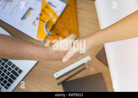 top view of two engineer shaking hand on wood table with tool and paper sheet Stock Photo