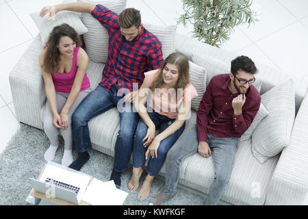 triumphant group of friends laughing while sitting on the couch in the living room Stock Photo