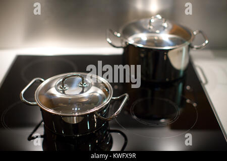 Two new stainless steel saucepans on modern kitchen range Stock Photo