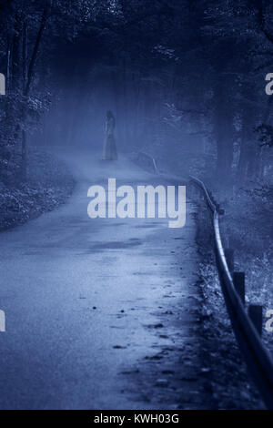 Mysterious Woman Ghost in White Dress in the Misty Forest Road, vintage noise filter Stock Photo