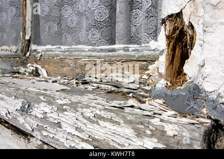 White paint peeling of an old, badly maintained, rotten, wooden windows frame. Stock Photo